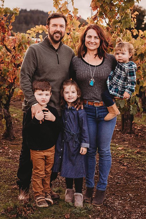 Andrew and April Nalle with their three young children in from of a vineyards filled with fall colors.
